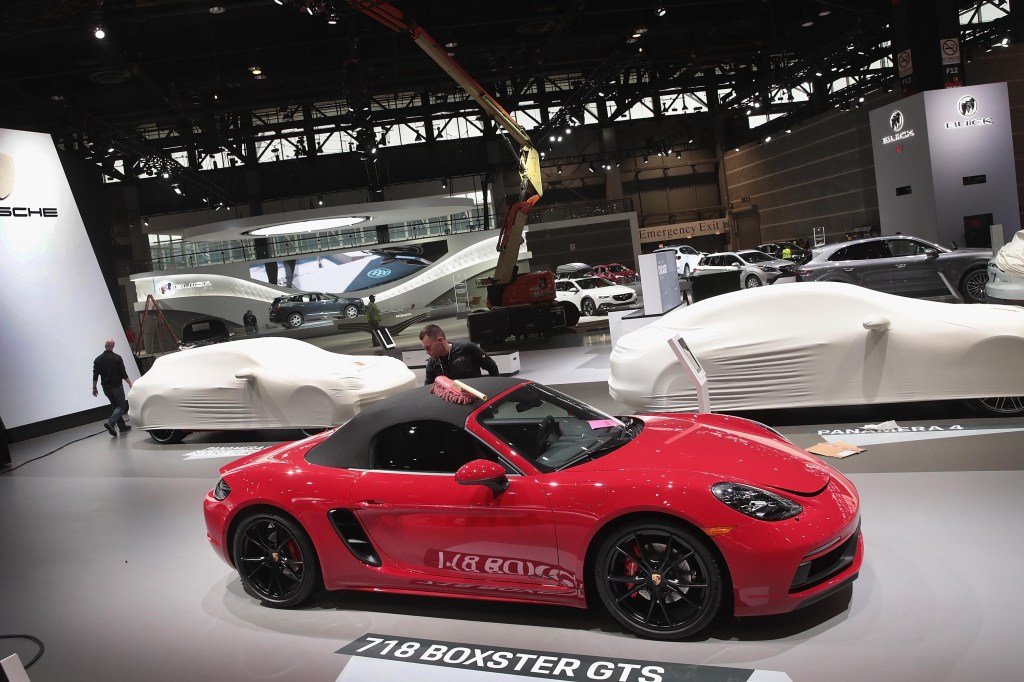 Workers prepare a red 20219-2021 Porsche 718 Boxster GTS sports car for the opening of the Chicago Auto Show