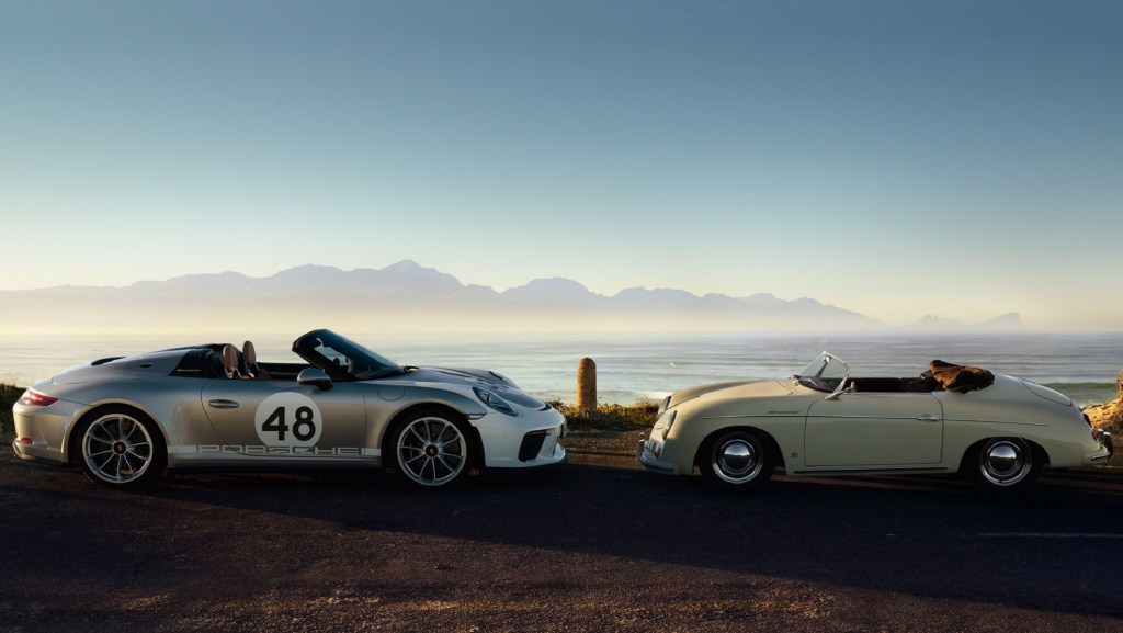 A white-and-silver 2019 Porsche 911 Speedster Heritage Edition next to a yellow 1954 Porsche 356 Speedster in front of the ocean
