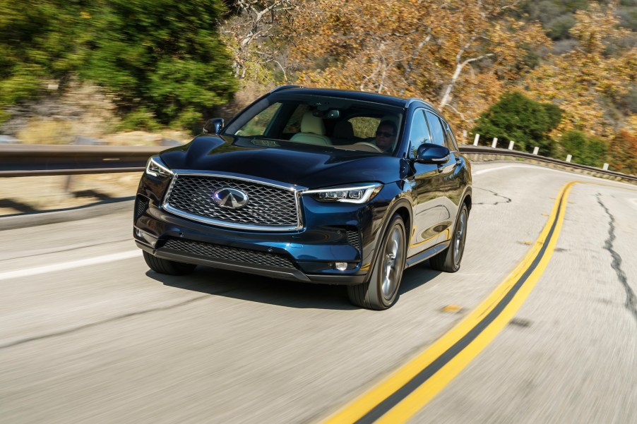 A blue 2020 Infiniti QX50 luxury compact SUV travels on a curvy mountain highway