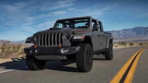 A gray 2020 Jeep Gladiator Mojave traveling on a two-lane highway in a mountainous desert