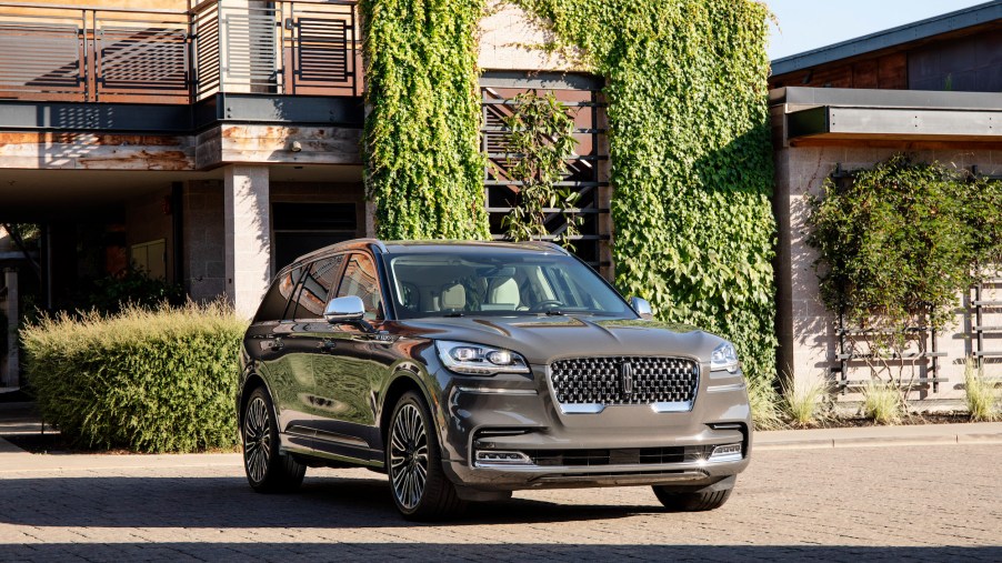 A gray 2020 Lincoln Aviator midsize crossover SUV parked outside a modern ivy-covered home