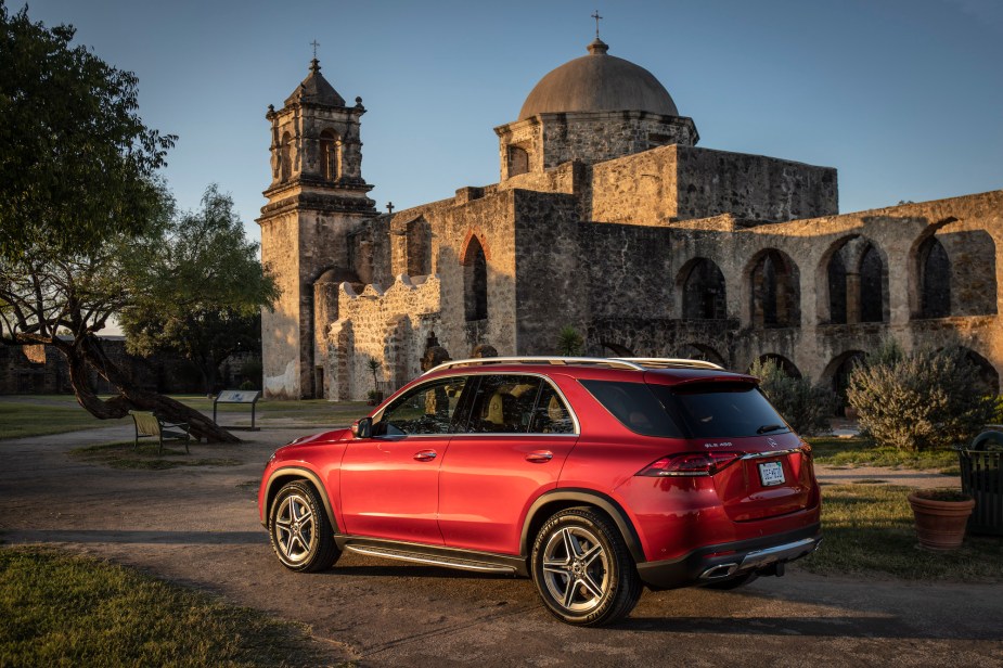 A red 2020 Mercedes-Benz GLE450 4MATIC compact luxury SUV parked outside the historic San José y San Miguel de Aguayo in San Antonio, Texas