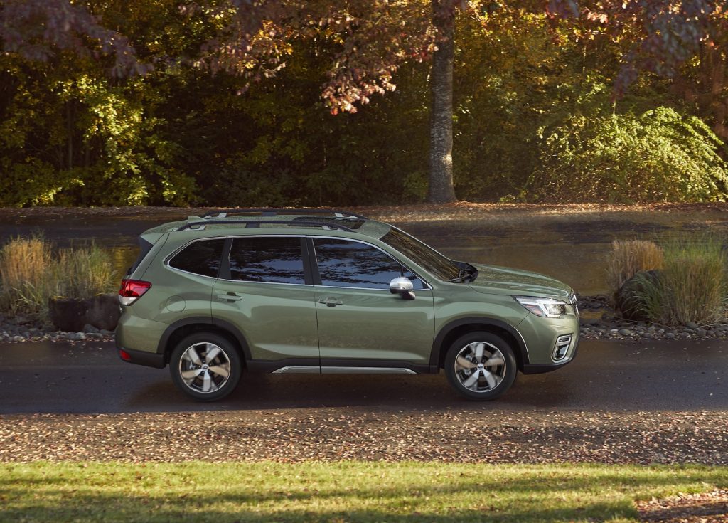 A green 2020 Subaru Forester compact crossover SUV parked on a sunny, tree-lined road