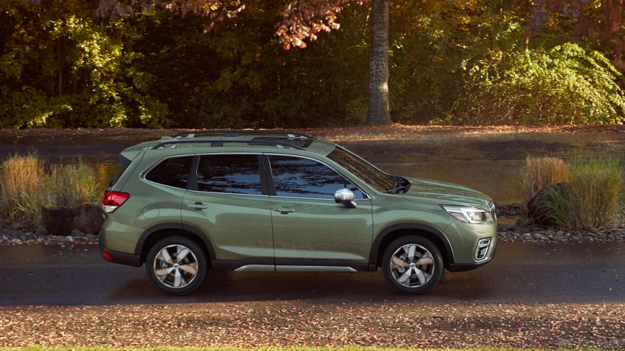 A green 2020 Subaru Forester compact crossover SUV parked on a sunny, tree-lined road