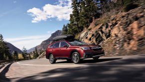 A red 2020 Subaru Outback driving down a highway road