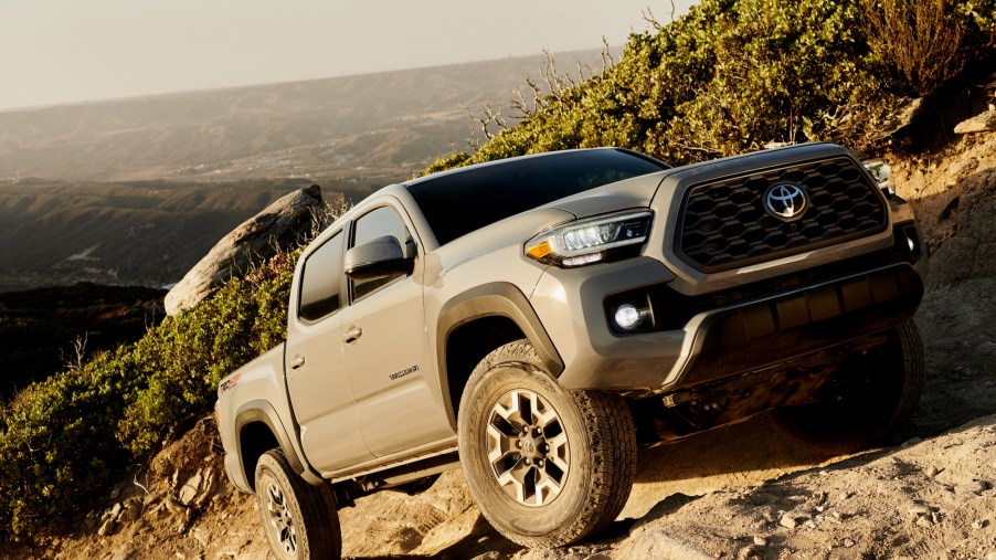 A gray 2020 Toyota Tacoma TRD Off-Road four-door pickup truck traversing rocky terrain on a mountainside