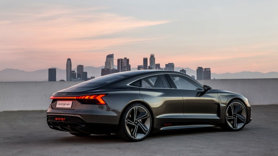 A dark-colored 2021 Audi e-tron GT concept in front of a cityscape and mountain range