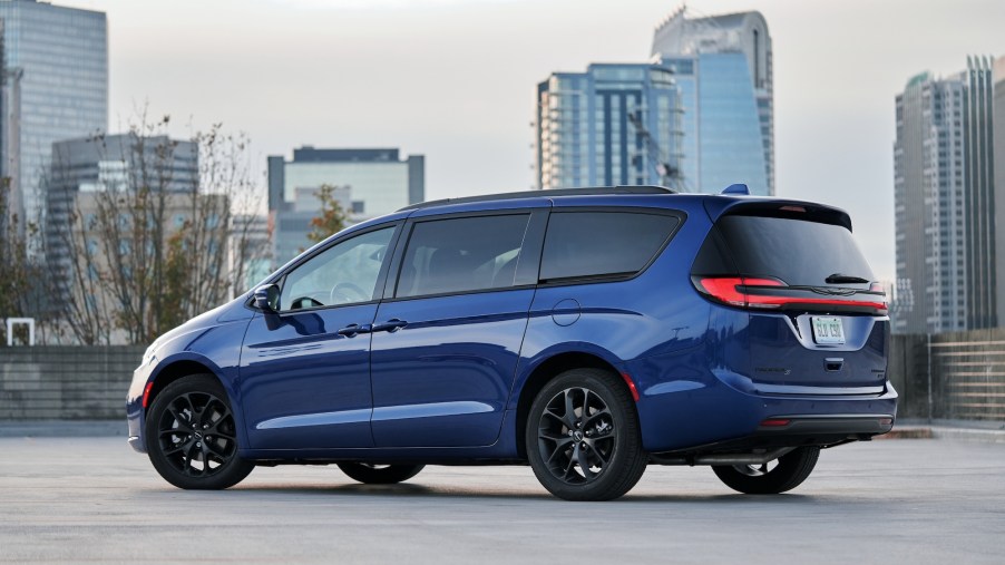 A blue 2021 Chrysler Pacifica Limited AWD S minivan parked in a lot with a cityscape in the background