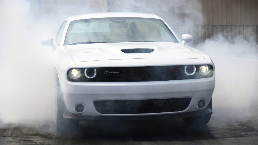 A white 2021 Dodge Challenger R/T Scat Pack surrounded in a cloud of smoke while drag racing