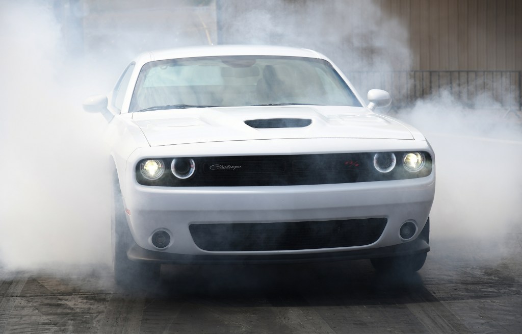A white 2021 Dodge Challenger R/T Scat Pack surrounded in a cloud of smoke while drag racing
