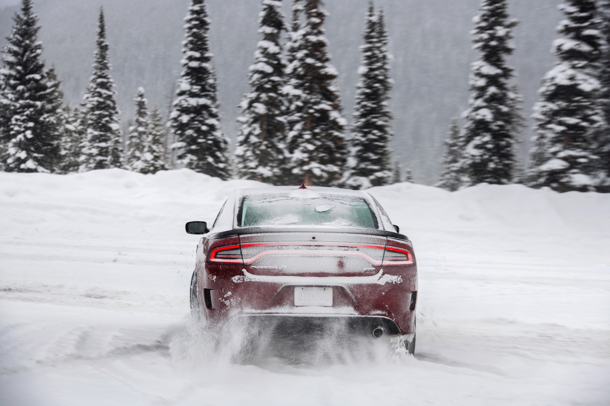 A rear view of a red 2021 Dodge Charger GT all-wheel drive driving in the snow