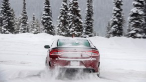A rear view of a red 2021 Dodge Charger GT all-wheel drive driving in the snow
