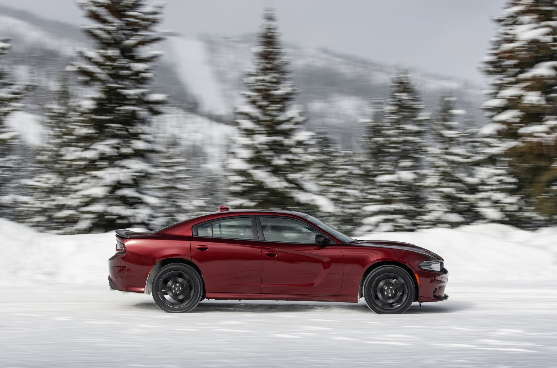 A red 2021 Dodge Charger GT AWD driving through the snow