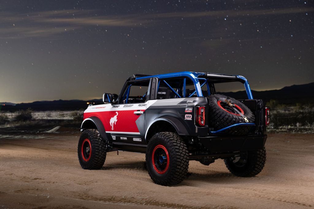 The rear 3/4 view of the red-white-and-blue 2021 Ford Bronco 4600 racer in the desert at night