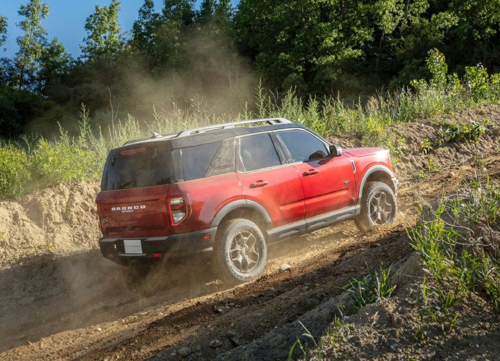 The rear 3/4 view of a red 2021 Ford Bronco Sport Badlands climbing a dusty off-road trail