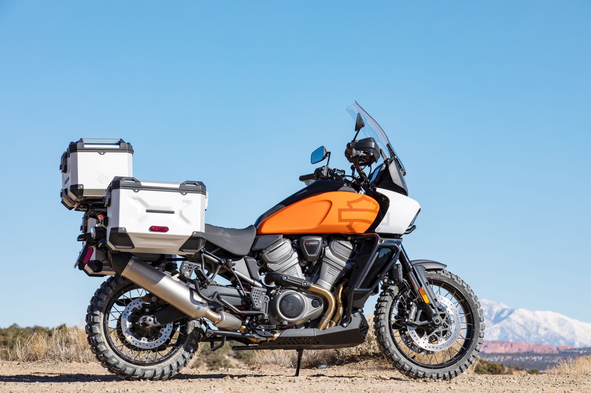 An orange 2021 Harley-Davidson Pan America 1250 Special in the desert equipped with accessory luggage cases