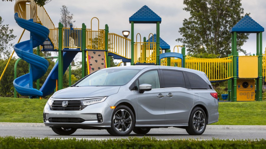 A silver 2021 Honda Odyssey parked in front of a blue and yellow playground