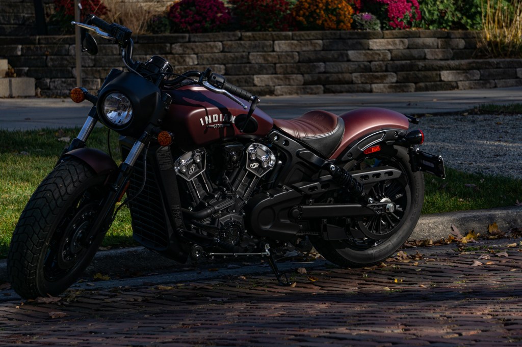 A maroon 2021 Indian Scout Bobber parked on a cobblestone street