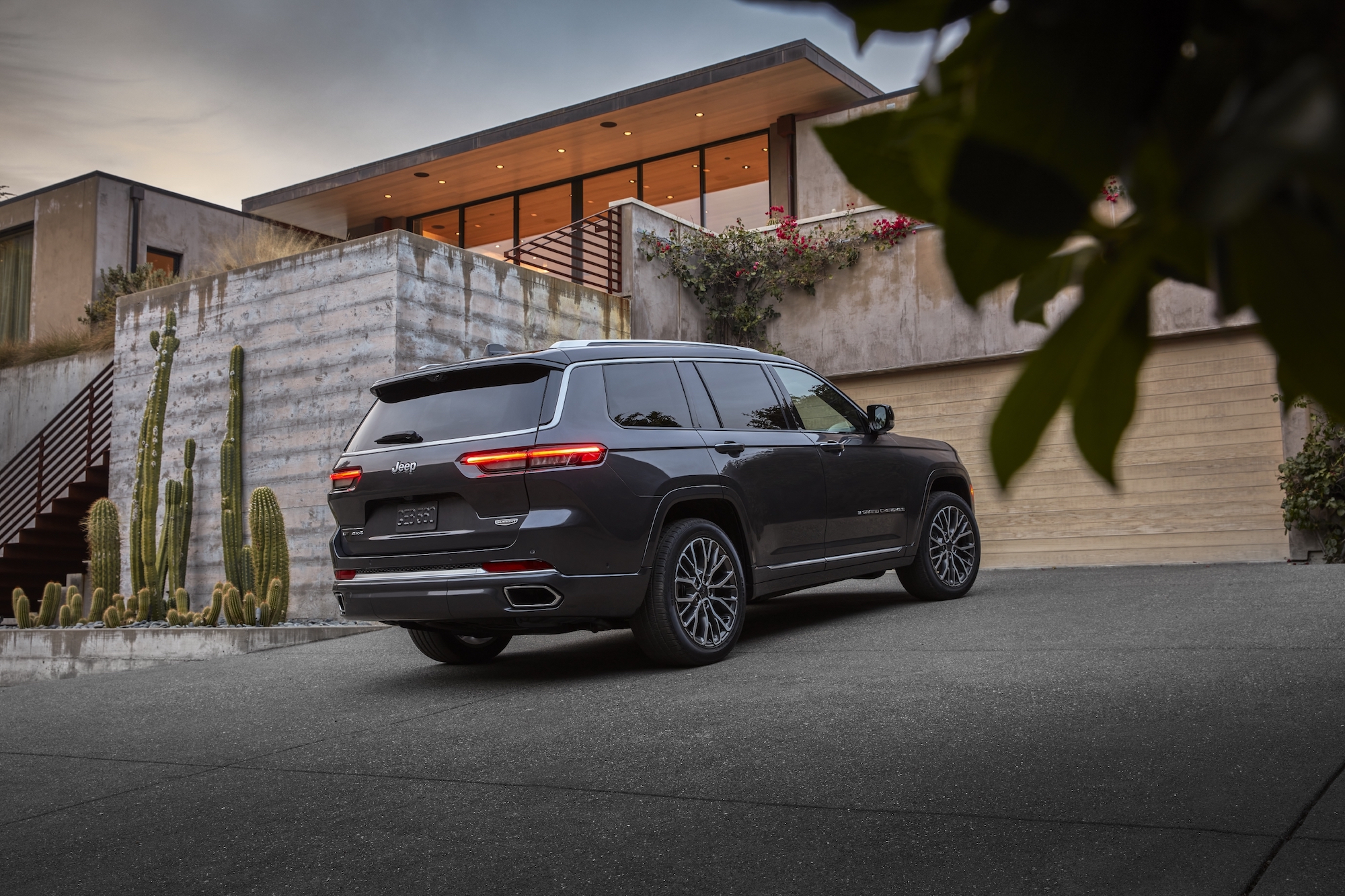A dark-gray 2021 Jeep Grand Cherokee L Summit Reserve parked in a modern desert home's driveway