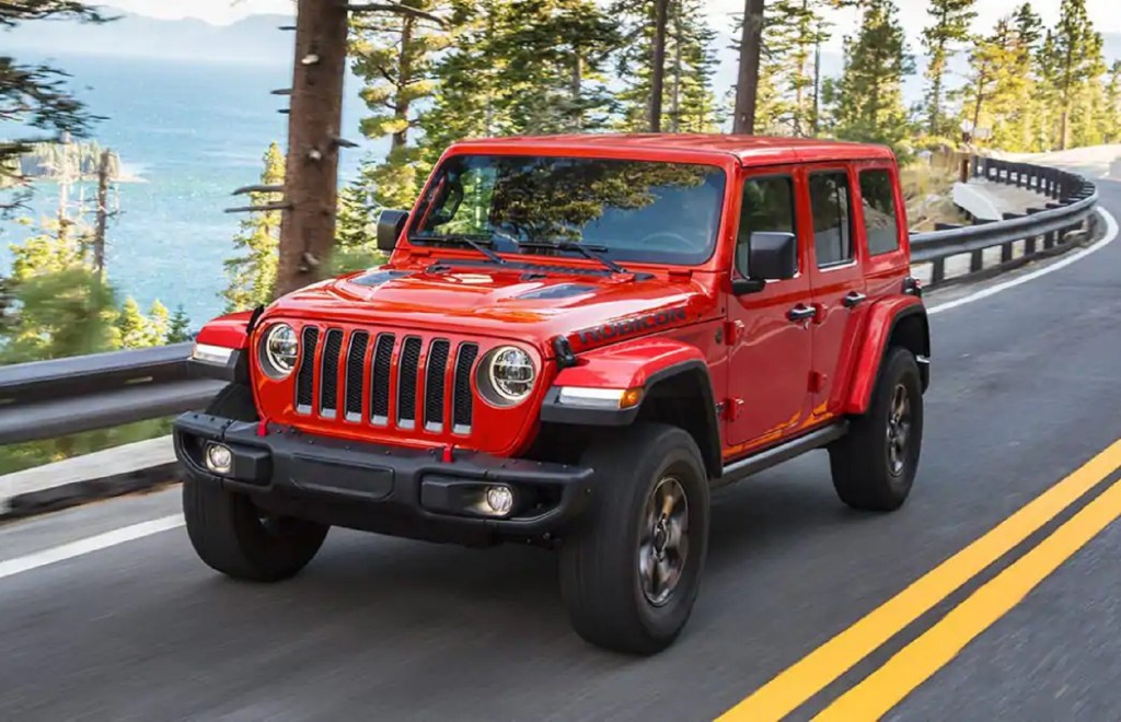 A red 4-door 2021 Jeep Wrangler Rubicon drives on a forest mountain road