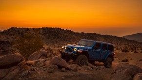 A blue 2021 Jeep Wrangler Rubicon 392 SUV parked on rocks at sunset in mountainous terrain