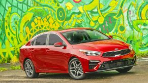 A red 2021 Kia Forte parked next to an artsy green wall