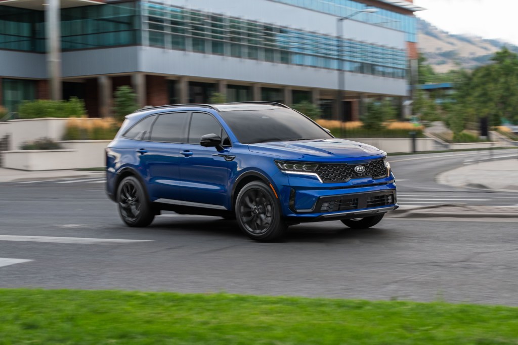 A blue 2021 Kia Sorento SX on display in a parking lot with a building in the background