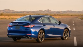A royal-blue 2021 Lexus ES parked on a rural road with mountains in the distance