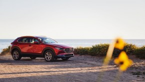 A red 2021 Mazda CX-30 parked on sand on a hill overlooking an ocean