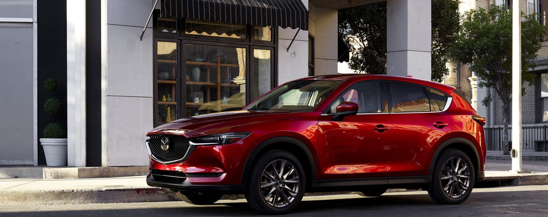 A luxurious red 2021 Mazda CX-5 parked in front of a building