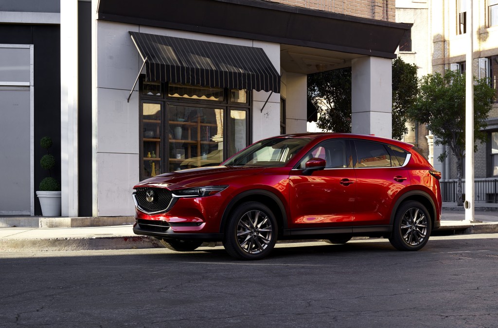 A luxurious red 2021 Mazda CX-5 parked in front of a building