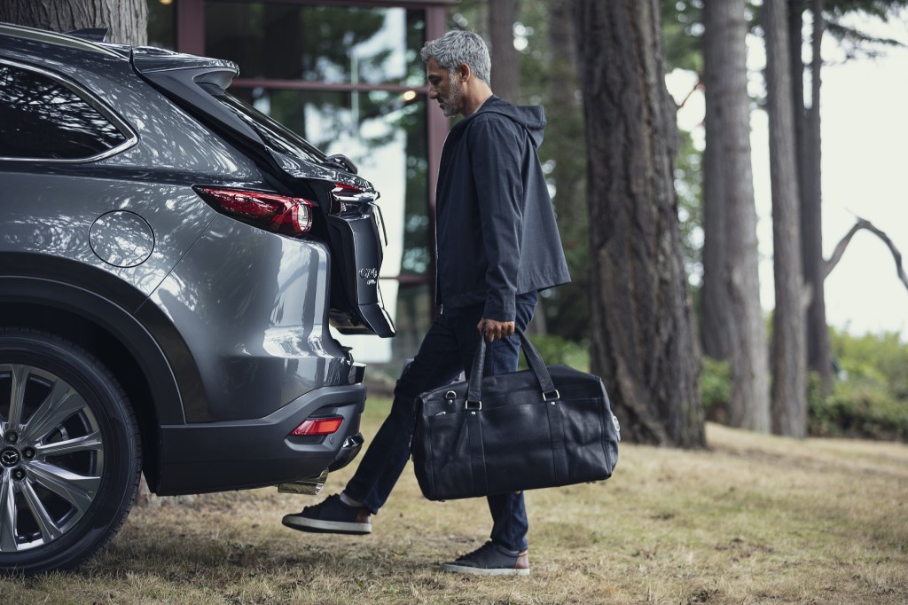 A man getting ready to put a bag in the 2021 Mazda CX-9's cargo area
