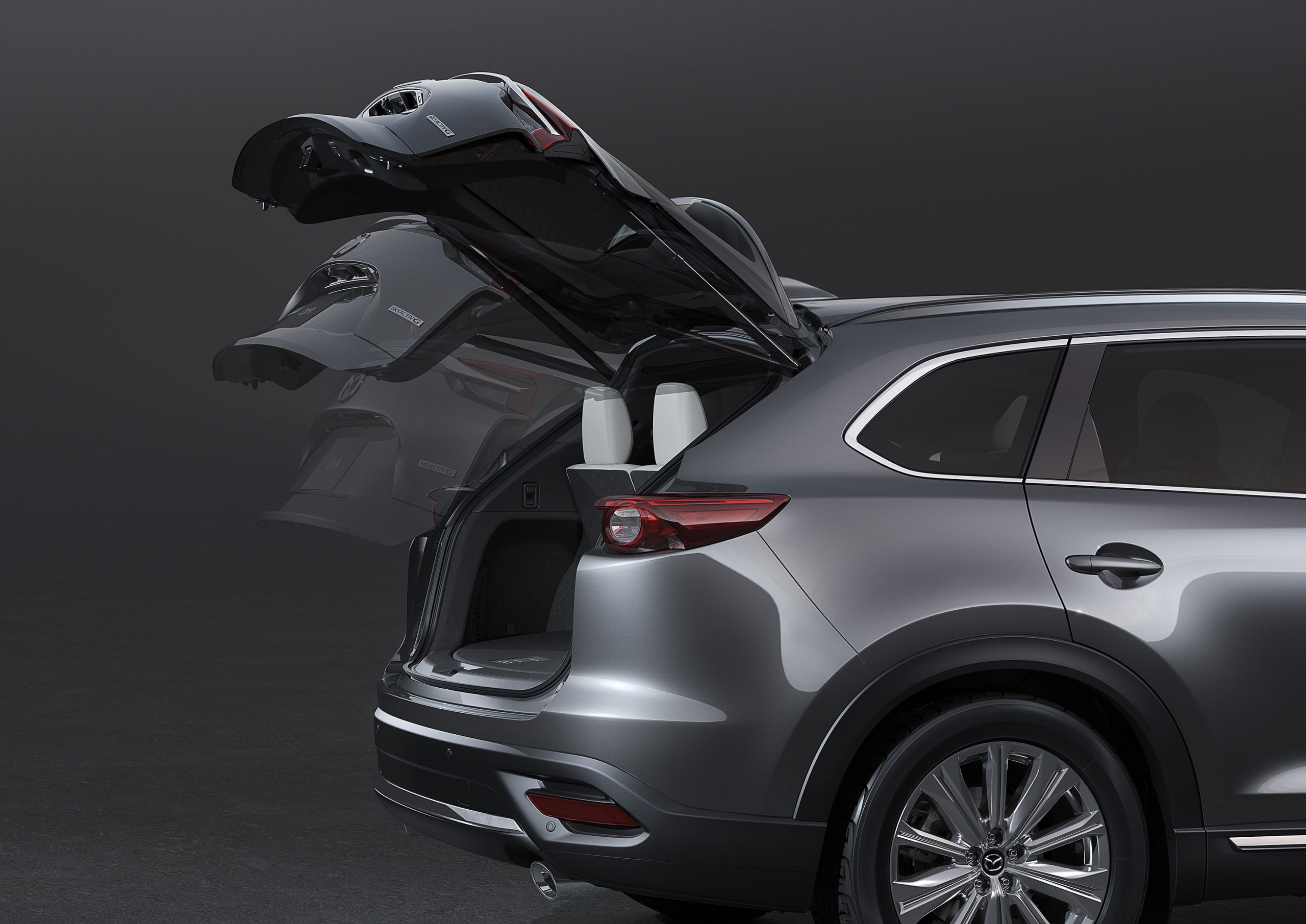 An action shot of a silver 2021 Mazda CX-9's liftgate opening, revealing its small cargo area.