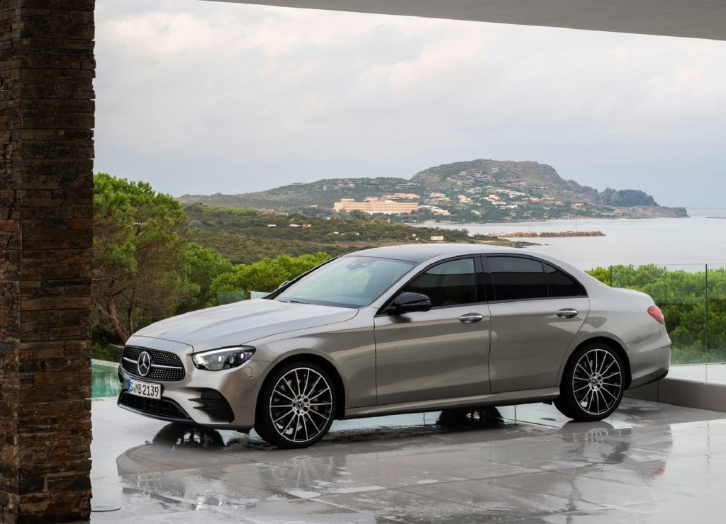 A tan 2021 Mercedes-Benz E-Class on a forested mountain overlooking a bayside city