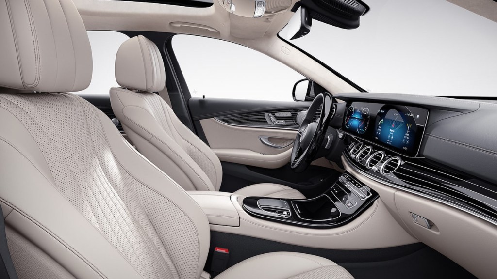 The beige-and-gray-leather front seats and piano-black-wood-trimmed dashboard of the 2021 Mercedes-Benz E450 4MATIC