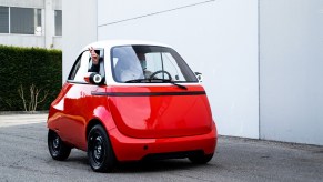 A red-and-white 2021 Microlino 2.0 pre-production prototype with two passengers