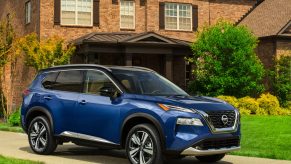 A blue 2021 Nissan Rogue parked in front of a house