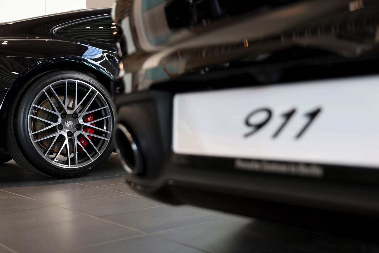 Two black 2021 Porsche 911 cars on display in a showroom