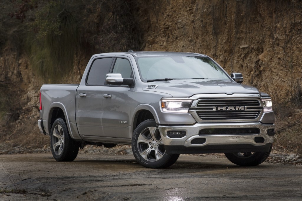 A silver 2021 Ram 1500 Laramie pickup truck parked on wet asphalt at the foot of a cliff