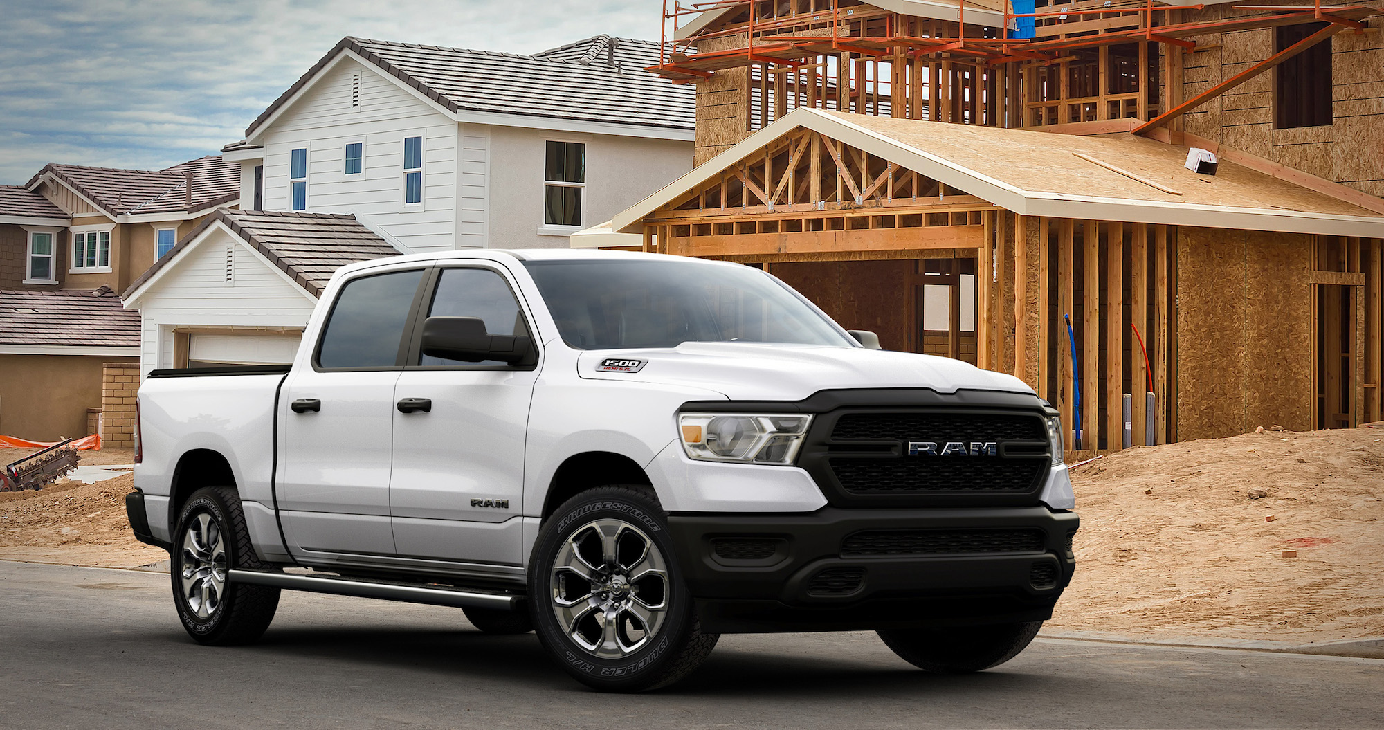 A white 2021 Ram 1500 Tradesman HFE EcoDiesel parked on the street outside a house under construction