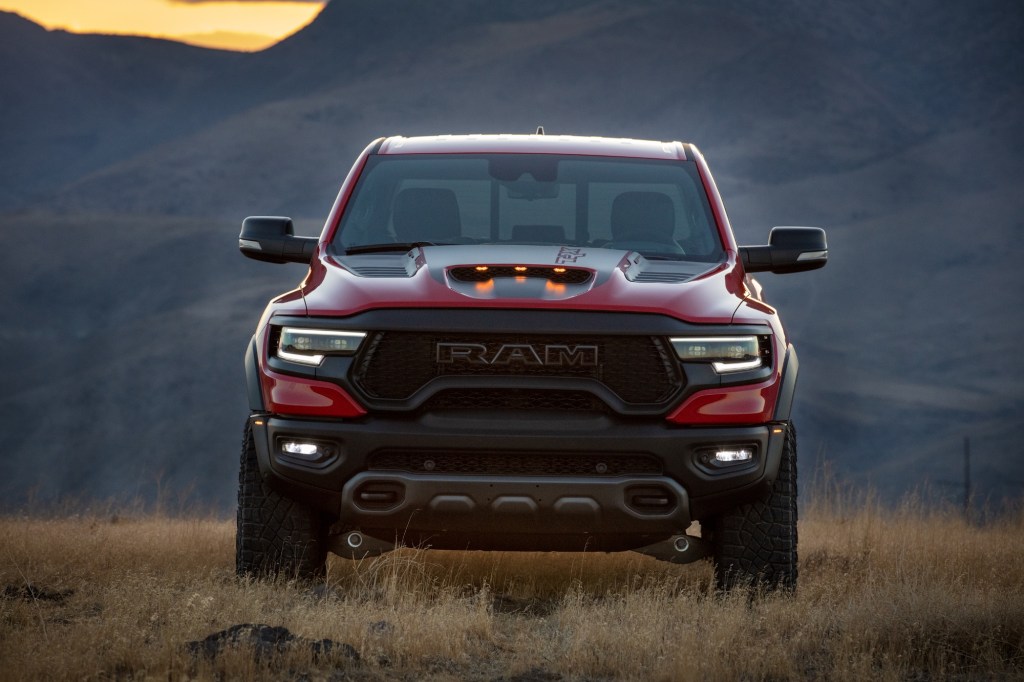 A red 2021 Ram 1500 TRX parked in a field of dry weeds in front of mountains at dusk