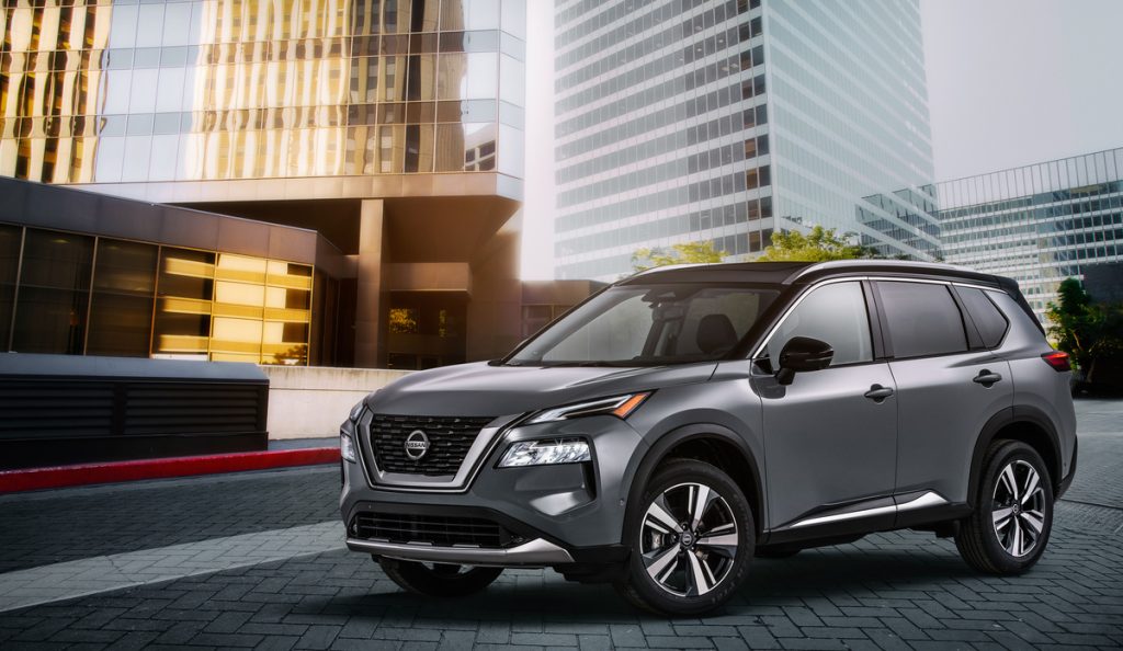 A side view of a gray 2021 Nissan Rogue Platinum AWD sitting parked in front of a building