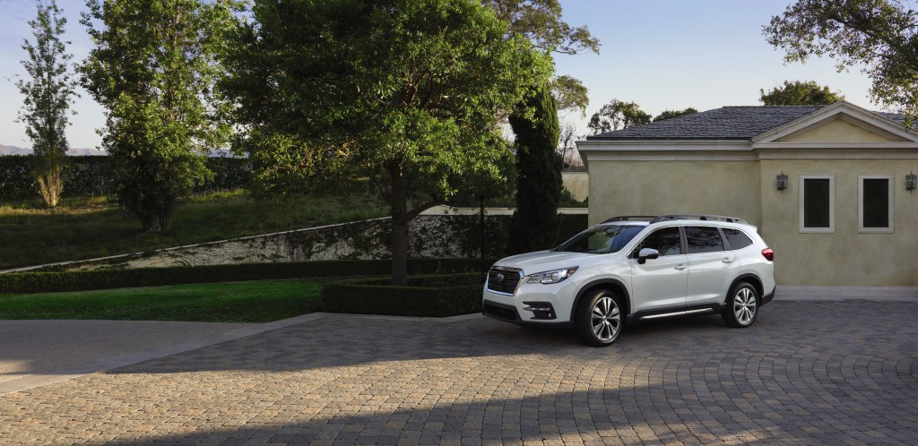 A white 2021 Subaru Ascent parked in the drive way in front of a house