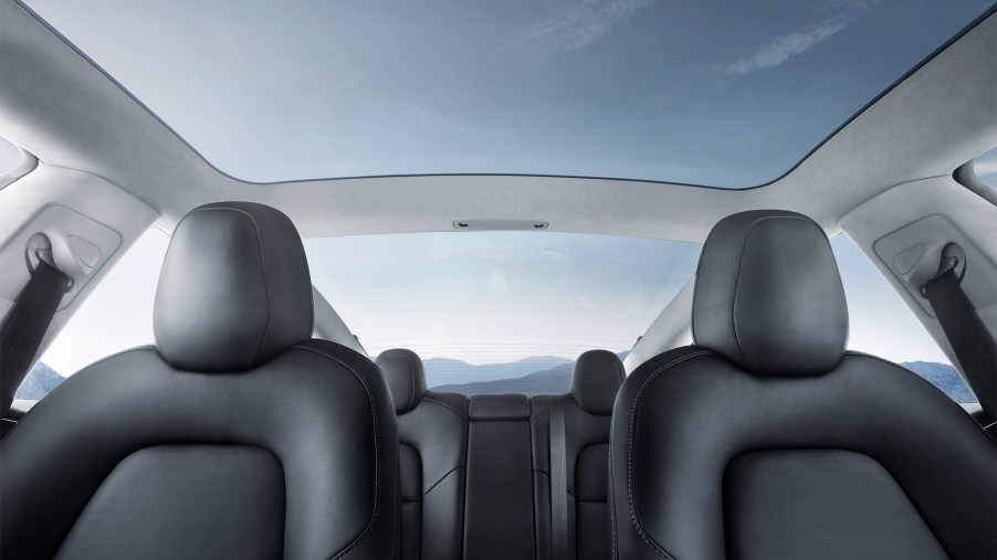 A 2021 Tesla Model 3's interior glass roof showing a blue sky with wispy clouds