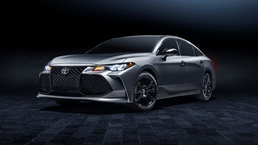 A silver 2021 Toyota Avalon XSE Nightshade full-size sedan parked on a black carpet in a dimly lit room