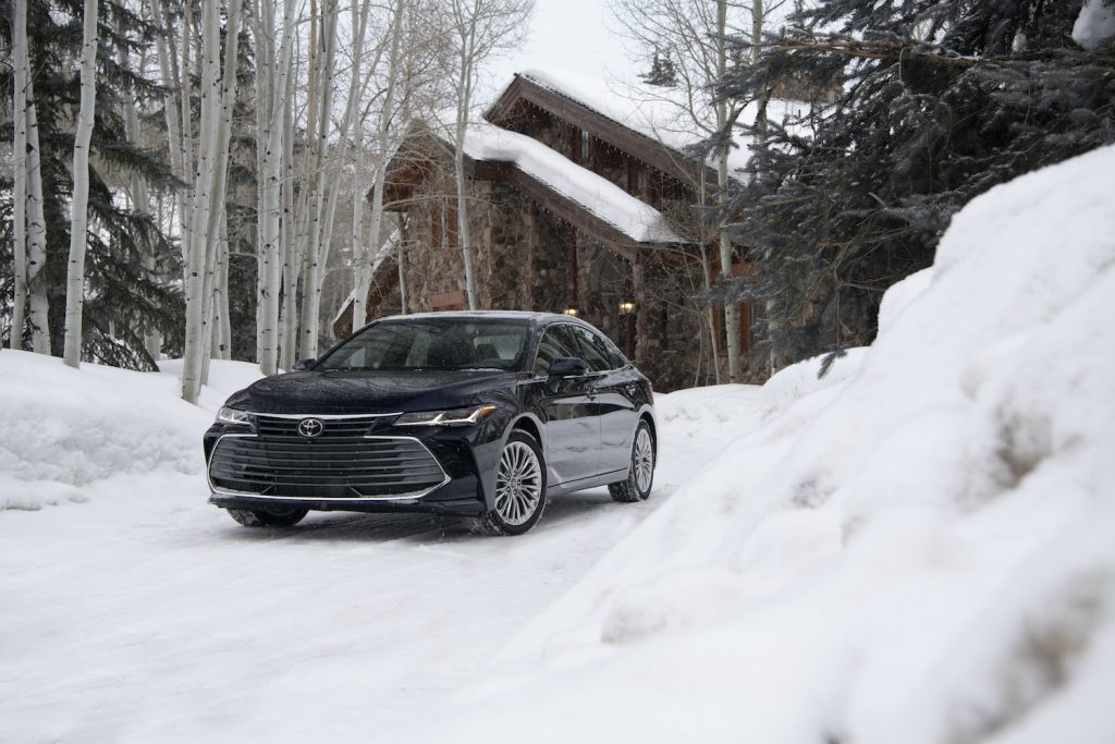 2021 Toyota Avalon parked in front of a winter cabin