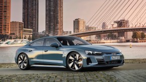 A blue-gray 2022 Audi E-Tron GT Quattro by a bayside city at sunset