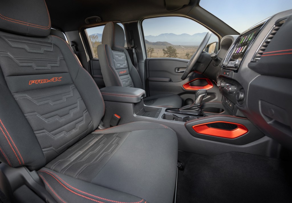 An interior shot of the 2022 Nissan Frontier showing off detailed dark-gray cloth seats with vibrant orange stitching