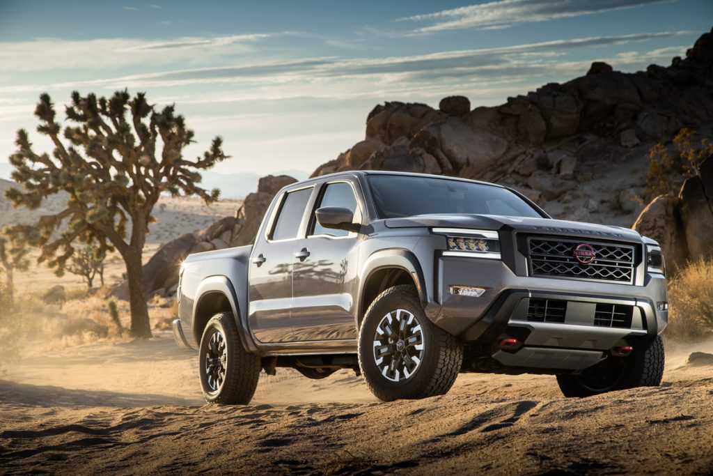 A gray 2022 Nissan Frontier sits parked among a rugged dessert terrain