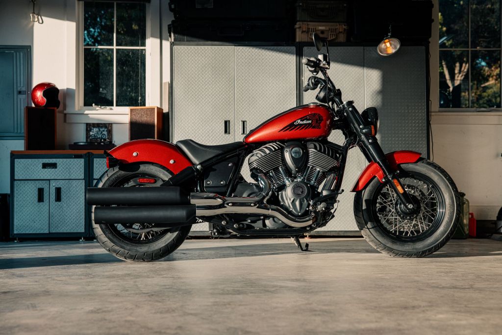 The side view of a red 2022 Indian Chief Bobber in a sunlit garage